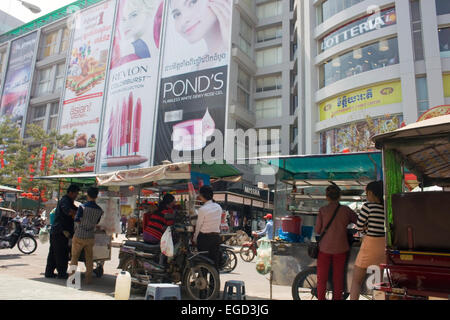 Women are working at a mobile food cart selling street food near a shopping mall on a busy city street in Phnom Penh, Cambodia. Stock Photo