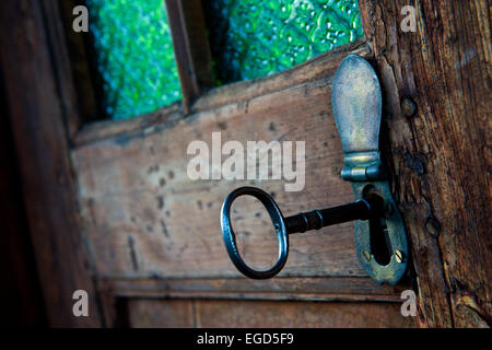 Key in lock in wooden door with stained glass Stock Photo