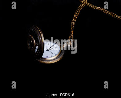 Vintage pocket watch showing five to twelve on black Stock Photo