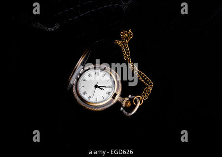 Vintage watch showing five minutes to twelve over black background Stock Photo