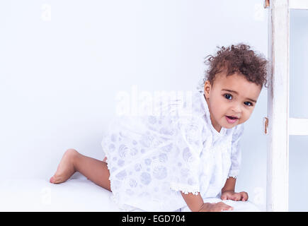 beautiful little girl smiling crawling on the white sofa Stock Photo