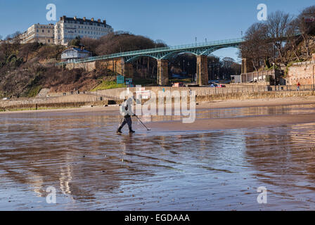 Man metal detecting on Scarborough Beach. In the background are the Spa Bridge and the Esplanade Hotel. Stock Photo