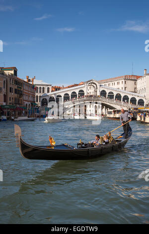Couple enjoying a ride in a gondola near the Rialto bridge on Grand Canal, Venice, Veneto, Italy, Europe Stock Photo