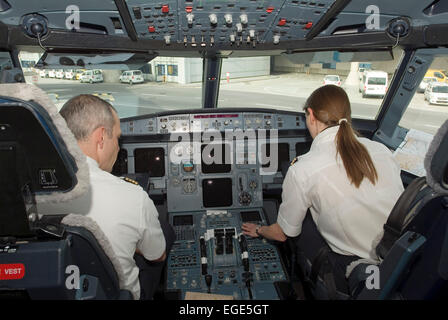 Aviation Cockpit of a  Airbus A320 plane aircraft passenger airliner jetliner with two staff Stock Photo