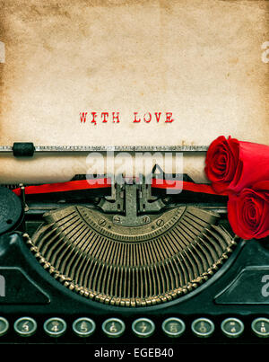 Vintage typewriter and red rose flowers. Aged textured grungy paper. Sample text With Love. Valentines Day concept Stock Photo