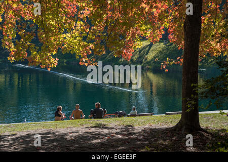 A group of people sitting on the grass, in front of the beautiful lake, in fall, in Lafontaine Park in Montreal Stock Photo