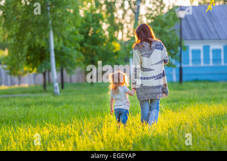 Mother and little daughter walking in sunny park Stock Photo