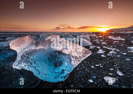 Broken ice from washed up Icebergs on Jokulsarlon black beach at sunset Jokulsarlon South east Iceland Stock Photo