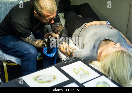 A woman being tattooed on her arm at the Brighton Tattoo Convention. Stock Photo