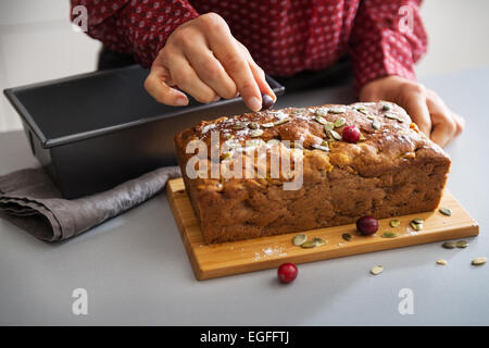 Closeup on young housewife decorating freshly baked pumpkin bread with seeds Stock Photo