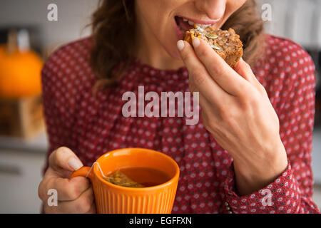 Closeup on young housewife drinking tea with freshly baked pumpkin bread with seeds Stock Photo