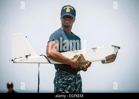 A US Navy sailor holds a RQ-20A  Aqua Puma aerial drone during assembly aboard the Military Sealift Command’s joint high-speed vessel USNS Spearhead February 10, 2015 off the coast of Ghana in the Atlantic Ocean. Stock Photo