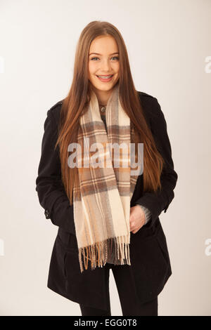 Pretty fifteen year old girl standing wearing a tartan scarf. Stock Photo
