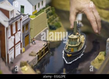 Hicksville, New York, USA. 22nd Feb, 2015. A model train club member reaches his hand down to position a model boat in an old fashioned dock scene with marine buildings displayed at the Model Train Exhibit hosted by Trainville Hobby Depot at the Broadway Mall. The person positioning the ship is the club member who built the scene. Donations were accepted at exhibit to support the Nassau County Empire State Games for the Physically Challenged. © Ann Parry/ZUMA Wire/Alamy Live News Stock Photo