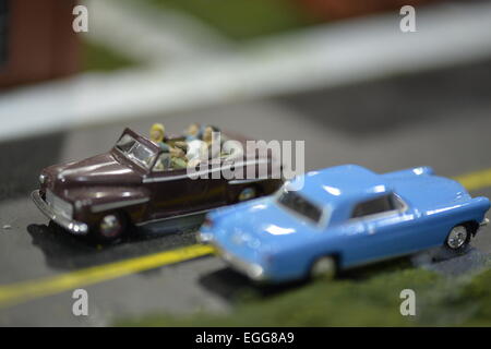 Hicksville, New York, USA. 22nd February 2015. A blue classic model car and brown model car with driver and passengers are in road scene display at the Model Train Exhibit is hosted by Trainville Hobby Depot at the Broadway Mall. Donations were accepted at exhibit to support the Nassau County Empire State Games for the Physically Challenged. Credit:  Ann E Parry/Alamy Live News Stock Photo
