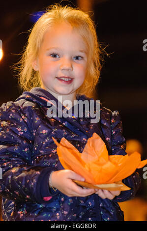 A young girl holds a paper Chinese lotus lantern, before placing it into the river to float away as part of a traditional ceremony. Stock Photo