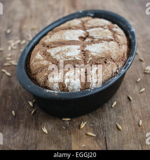 Freshly baked sourdough rye bread in oval bread pan on wooden table Stock Photo