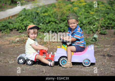 boy and girl on toy cars involved in an accident Stock Photo