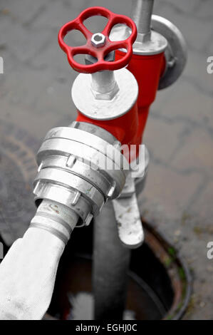 Detail shot with a white hose connected to a red hydrant Stock Photo