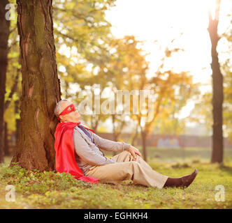 Senior in superhero outfit leaning on tree in park shot with tilt and shift lens Stock Photo