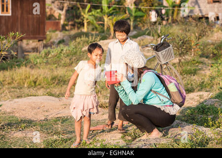 Asian woman from Hong Kong showing photographs she has taken of these children at village on bank of Inle Lake,Burma,Myanmar. Stock Photo