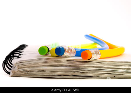 Four colorful pencils that are all strangely bend, lying on a notebook. Stock Photo