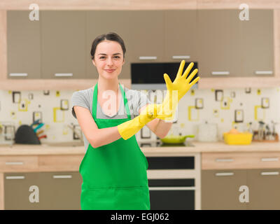 young happy woman putting rubber gloves and getting ready for cleaning ...