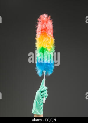 hand holding up synthetic feather duster against grey background Stock Photo