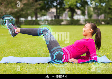 smiling woman doing exercises on mat outdoors Stock Photo