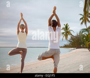couple making yoga exercises on beach from back Stock Photo