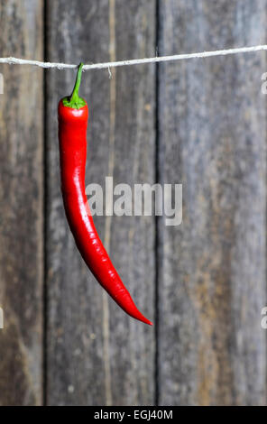 Frische rote Chilischote hängt an Schnur vor Holzwand Stock Photo