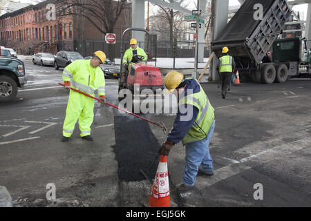 Workers fill in and repair a street that has new gas pipes underneath in the Carroll Gardens neighborhood of Brooklyn, NY. Stock Photo