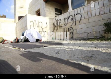 Feb. 25, 2015 - Bethlehem, West Bank, Palestinian Territory - Palestinian pray outside the burnt mosque in the West Bank village of Jab'a, near Bethlehem, just south of Jerusalem, in an apparent attack by Jewish settlers overnight on 25 February 2015. Hate graffiti was spray painted on the building including a Star of David it what authorities believe is a 'price tag ' act of vandalism. The head of Jab'a village council Numan Hamdan said residents detected the fire and were able to put it out before it spread to the rest of the mosque, the Palestinian news agency WAFA reported. Damage was caus Stock Photo