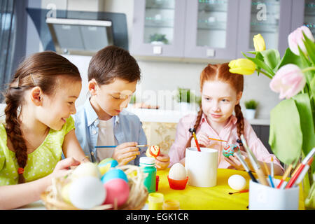 Little friends painting Easter eggs in the kitchen Stock Photo