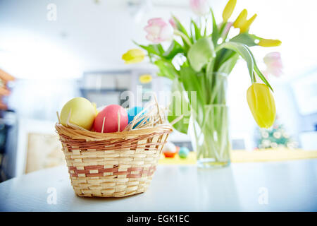Easter eggs in basket with bunch of tulips on background Stock Photo