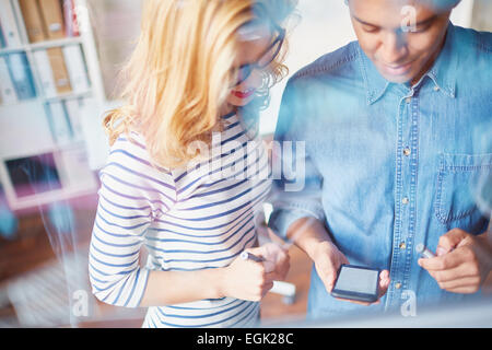 Two co-workers using smartphone for browsing data Stock Photo