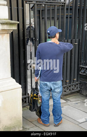 London, England, UK. Man delivering flowers (Interflora) to Downing street - waiting by the security gate Stock Photo