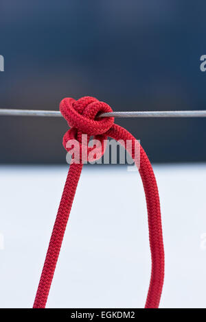 Red mooring rope tied around a lifeline. Vertical shot Stock Photo