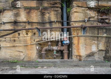 Old rusty industrial pipes in a wall. Stock Photo