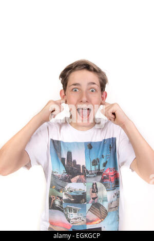 White Teenage Boy with his fingers in his ears looking shocked. Studio Shot Stock Photo