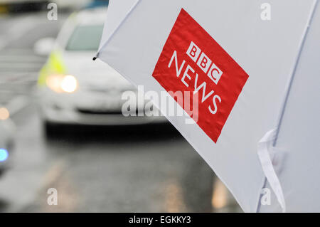 Ballyclare, Northern Ireland. 11th September 2013 -  Journalist holds a BBC News umbrella while watching police activity Stock Photo