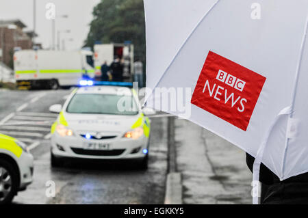 Ballyclare, Northern Ireland. 11th September 2013 -  Journalist holds a BBC News umbrella while watching police and army activity Stock Photo