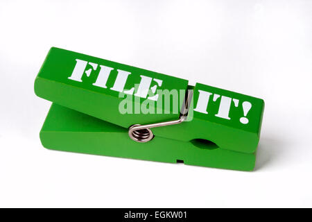 Close up image on white background of a wooden clothes peg with a metal spring printed with the words FILE IT for use as a desktop clip for paperwork Stock Photo