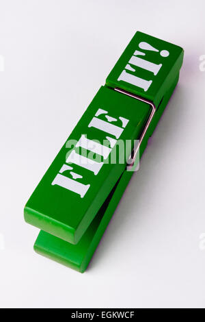 Close up image on white background of a wooden clothes peg with a metal spring printed with the words FILE IT for use as a desktop clip for paperwork Stock Photo