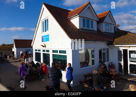 Customers sitting outside the Bluebird beach cafe on Ferring beach in the winter sunshine Stock Photo