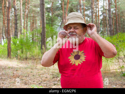Senior man tasting new home-grown tobacco with cigarette rolled by himself Stock Photo