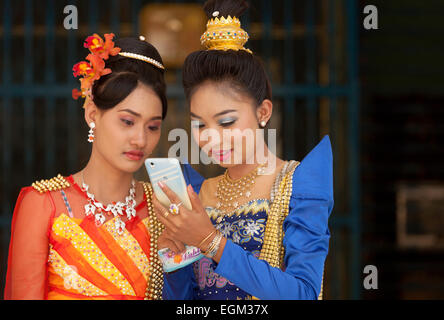 Two young women using their mobile phone, Mandalay, Myanmar ( burma ), Asia Stock Photo