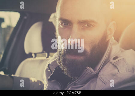 Young handsome man driving his car on a beautiful sunny day. Retro tones. Stock Photo