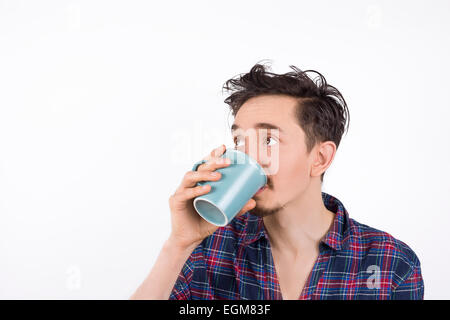 Portrait of a man wearing pajamas drinking coffee or tea and looking to his right. Isolated on white Stock Photo