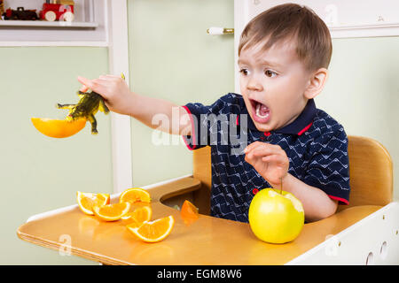 Small boy playing around with fruit and acting silly Stock Photo